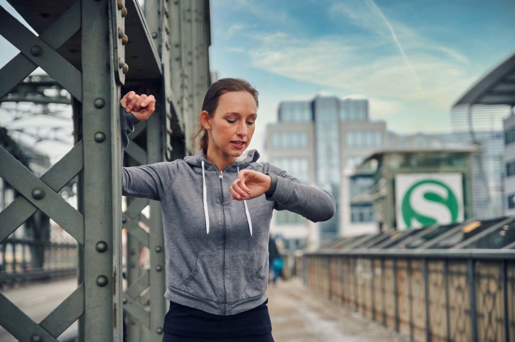 Junge Frau überprüft ihre Vitalwerte auf einer Smartwatch
